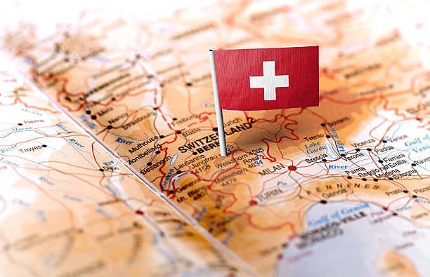 The flag of Switzerland pinned on the map. Horizontal orientation. Macro photography.