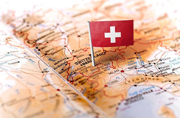 The flag of Switzerland pinned on the map. Horizontal orientation. Macro photography.