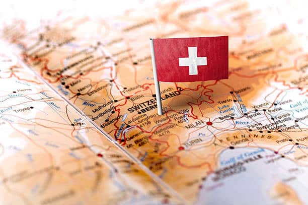 The flag of Switzerland pinned on the map. Horizontal orientation. Macro photography.